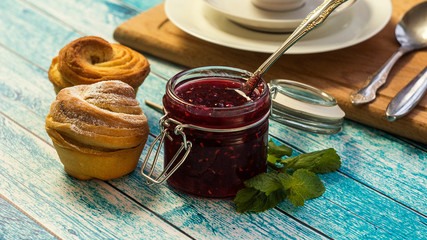 raspberry jam in a jar and muffins. selective focus