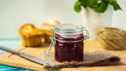 raspberry jam in a jar and muffins. selective focus