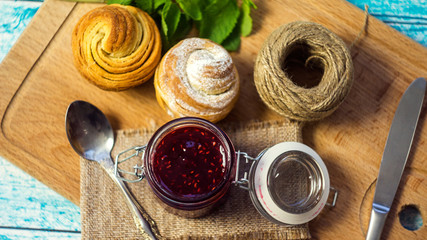 raspberry jam in a jar and muffins. selective focus, top view