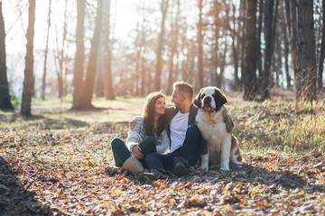 Young couple enjoying nature outdoors together with their Saint Bernard puppy. 