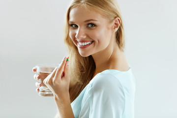 Beautiful Smiling Woman Taking Vitamin Pill. Dietary Supplement