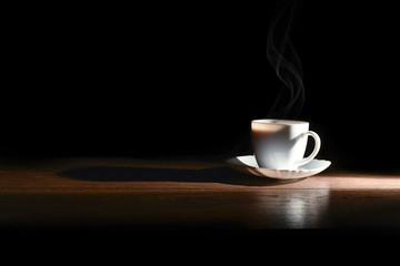 White cup of hot coffee on the table and a dark background