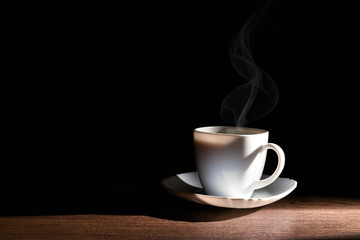 White cup of hot coffee on the table and a dark background