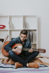teen in the room playing the guitar