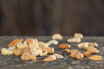 Raw and roasted cashew nuts on old wooden board. Healthy food.