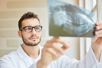 Zahnarzt schaut auf Röntgenbild