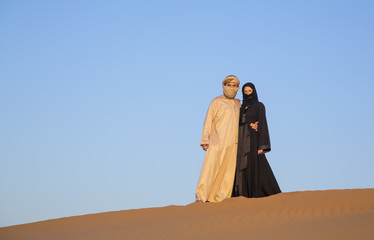 Couple in traditional clothing in a desert near Dubai - obrazy, fototapety, plakaty
