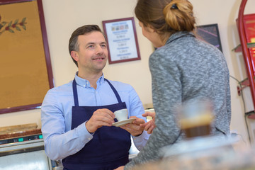 Man serving coffee to businesswoman