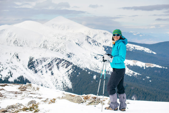 Girl in colorful sportswear standing on top of a winter mountain