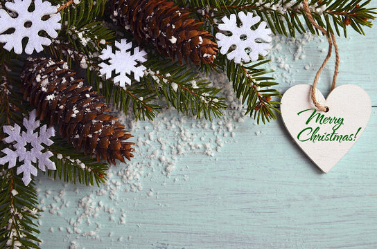 Merry Christmas greeting card.Decorative snowflakes,fir cones,heart and snowy fir tree branch on light blue background.Christmas decoration.Selective focus.