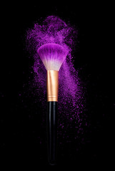 make-up brush with powder dust isolated on black