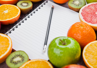 Fruits mix grapefruit orange apples with notebook