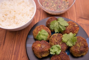 Asian, thai or vietnam style fish and vegetable burgers or fritters with fresh coriander leaves served with boiled rice and homemade fresh sweet chili sauce consist from chili, cucumber, soy sauce.