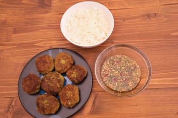 Detailed pictures on the asian thai or vietnam style fish and vegetable burgers or fritters, served with boiled rice and homemade fresh sweet chili sauce consist from chili, cucumber, soy sauce.