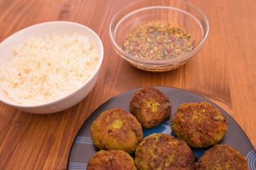 Detailed pictures on the asian thai or vietnam style fish and vegetable burgers or fritters, served with boiled rice and homemade fresh sweet chili sauce consist from chili, cucumber, soy sauce.