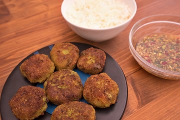 Detailed pictures on the asian thai or vietnam style fish and vegetable burgers or fritters, served with boiled rice and homemade fresh sweet chili sauce consist from chili, cucumber, soy sauce.