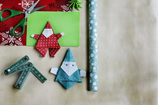 Figuras para decoraci&oacute;n navide&ntilde;a hechas de papel con t&eacute;cnica origami, tijeras y regla sobre fondo de papel texturizado. Imagen capturada utilizando la suave luz de una ventana. Plano cenital.