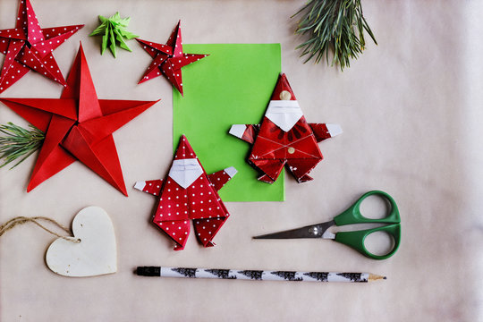 Figuras para decoración navideña hechas de papel con técnica origami, tijeras y lapicero sobre fondo de papel texturizado. Imagen capturada utilizando la suave luz de una ventana. Plano cenital