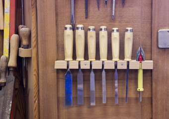 carving knives and screwdrivers hanging on wooden wall