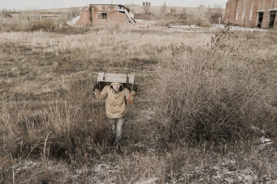boy carries a wooden box. The boy found the artifact. wanderer in the world of the apocalypse. boy in a protective cloak and hood.  a child soldier. young boy soldier. abandoned military base