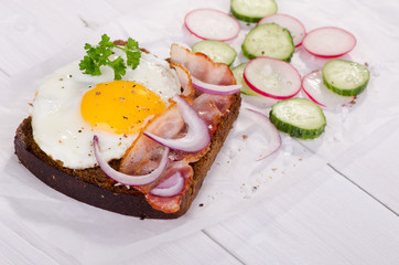 Toast with fried egg and bacon on rye bread