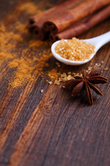 Sticks and powder of cinnamon, anise, sugar cane on the wooden background. selective focus