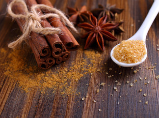 Sticks and powder of cinnamon, anise, sugar cane on the wooden background. selective focus