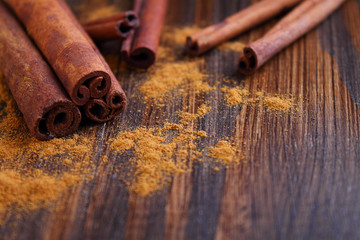 Sticks and powder of cinnamon, anise, sugar cane on the wooden background. selective focus