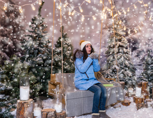 Woman in blue down jacket blows snowflakes while sitting on a sw