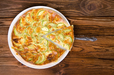 Pie with zucchini on the wooden table, top view.