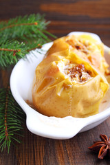 apples baked with honey and nuts in a white plate on a dark background