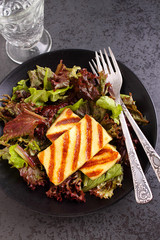 green salad with fried halloumi cheese on a black plate