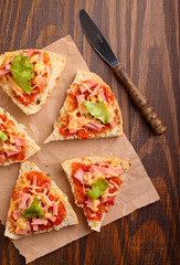 Pizza slices on parchment on wooden background