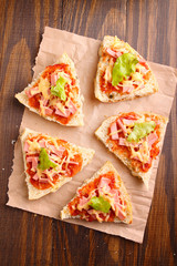 Pizza slices on parchment on wooden background