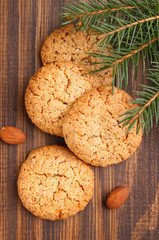 Almond cookie on a brown wooden background, the branches of spruce