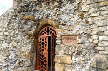 the entrance to the ancient Muslim shrine and mausoleum with a metal door. Entrance to the old building of natural stone