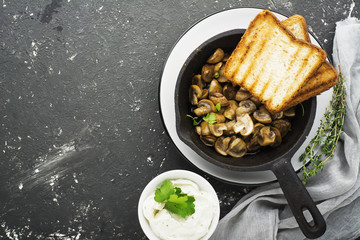 Fried mushrooms in a pan with  batch curd cheese on crispy toast for breakfast. Top view