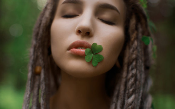 Very beautiful girl with a clover in her lips. Beauty and nature concept