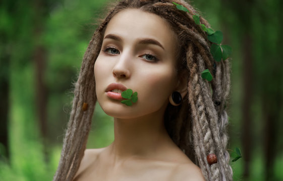 Very beautiful girl with a clover in her lips and hair. Beauty and nature concept