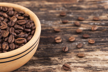 Wooden bowl and coffee grains on grunge wooden background
