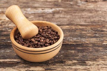 Wooden bowl and coffee grains on grunge wooden background