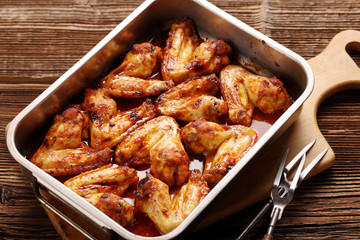 Chicken wings baked in a pan on wooden background
