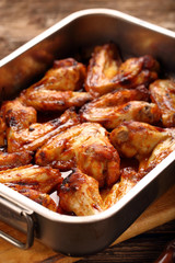 Chicken wings baked in a pan on wooden background
