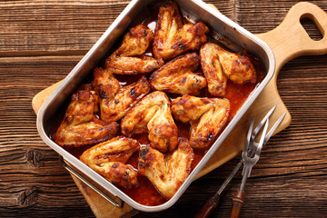 Chicken wings baked in a pan on wooden background