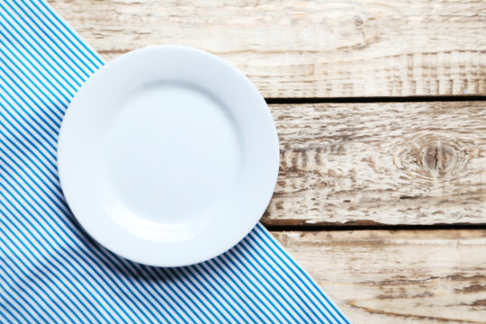 Empty plate with napkin on brown wooden table