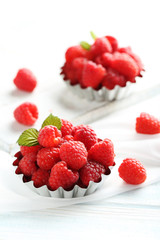 Red raspberries in bowl on a white wooden table
