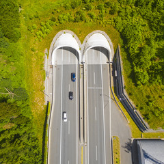 Aerial view of highway tunnel in mountains. Traffic on the road. Transportation from above....