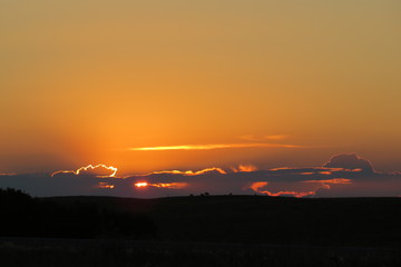 Sunset behind clouds in a Saskatchewan field, Canada.