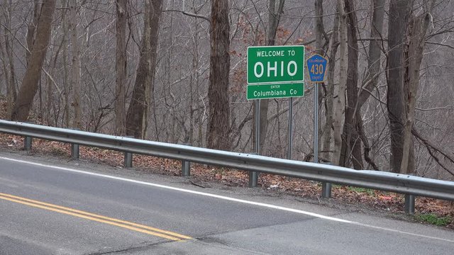 An establishing shot of a Welcome to Ohio road sign in the Autumn.
