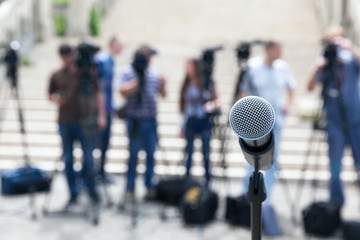 Microphone in focus against blurred camera operators and journalists. Press conference. - obrazy, fototapety, plakaty